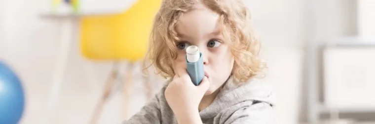 kleines maedchen mit grauem kapuzenpulli und blauen augen mit asthma das asthma medikamente haelt