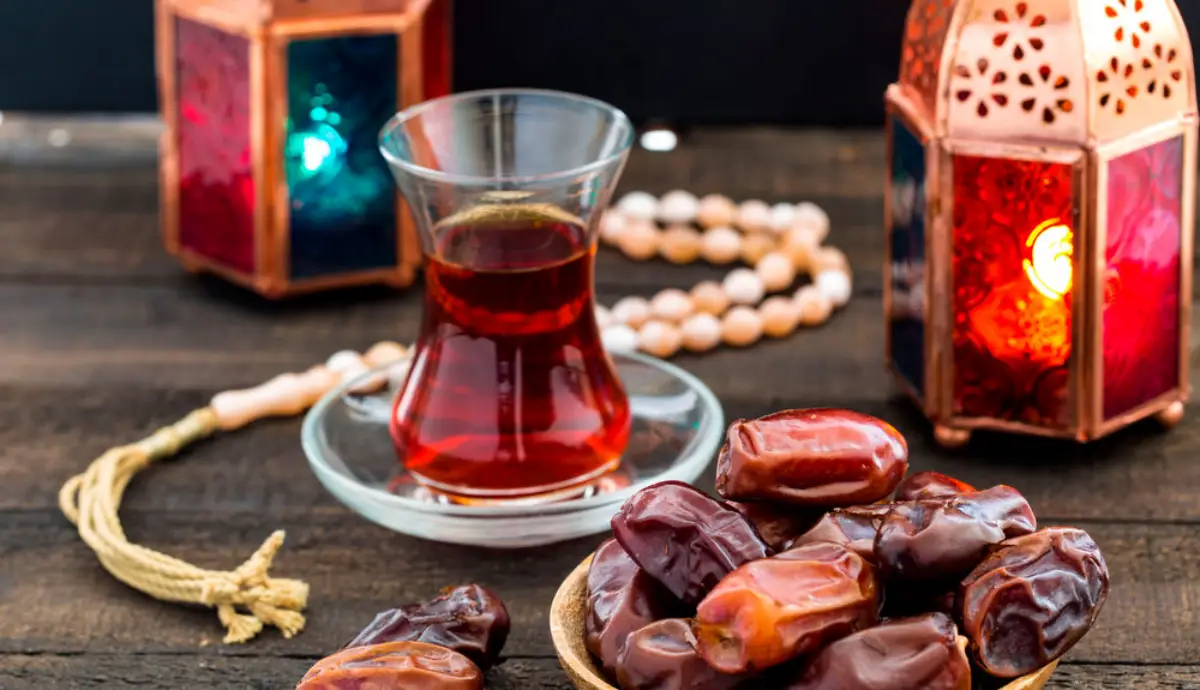 ramadan kareem festive close up of dates on wooden plate and rosary with oriental lantern lamps and cup of black tea on wood background islamic holy month greeting card