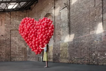 valentinstag alleine verbringen was zieht man zum valentinstag an frau in grosser halle rote ballone in herzform