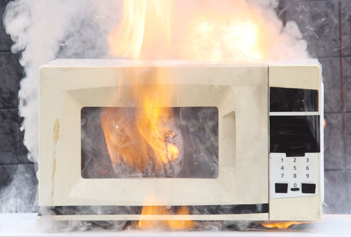 weiße mikrowelle brennt mit feuer und funken aufgrund von mikrowellen probleme