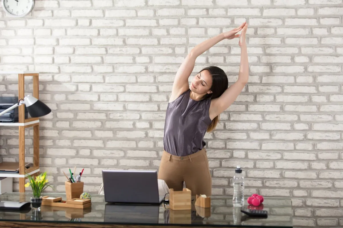 yoga stretch im büro frau graues top hose in beige