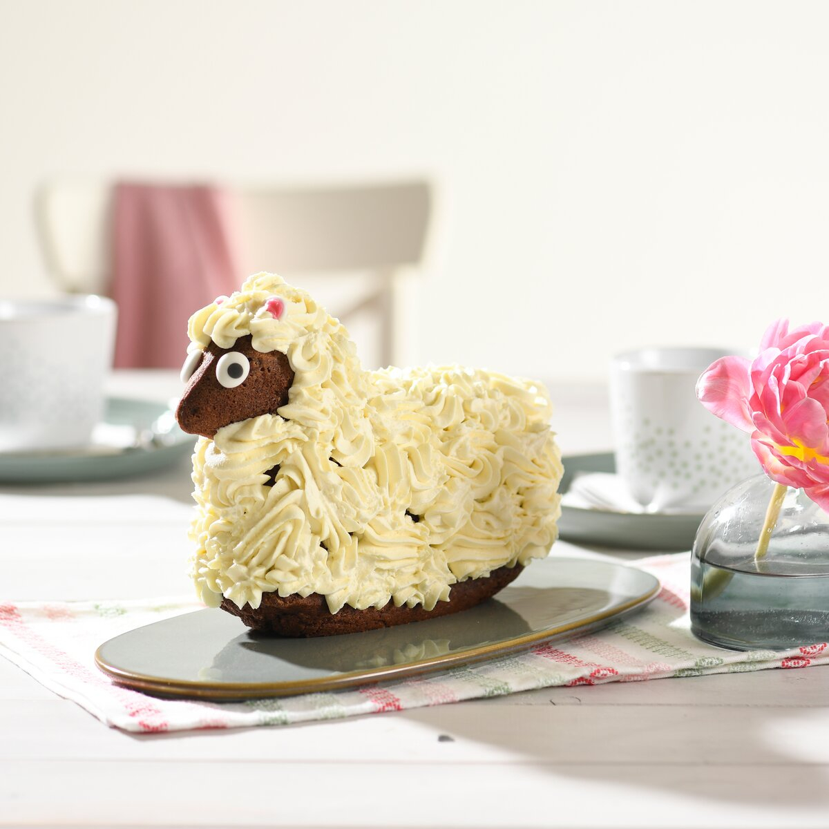 osterlammkuchen mit weißem glasur überzogen neben rosa blume