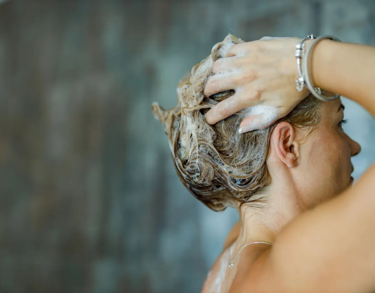 haare stylen mit glaetteisen frau unter der dusche shampooniert ihre haare