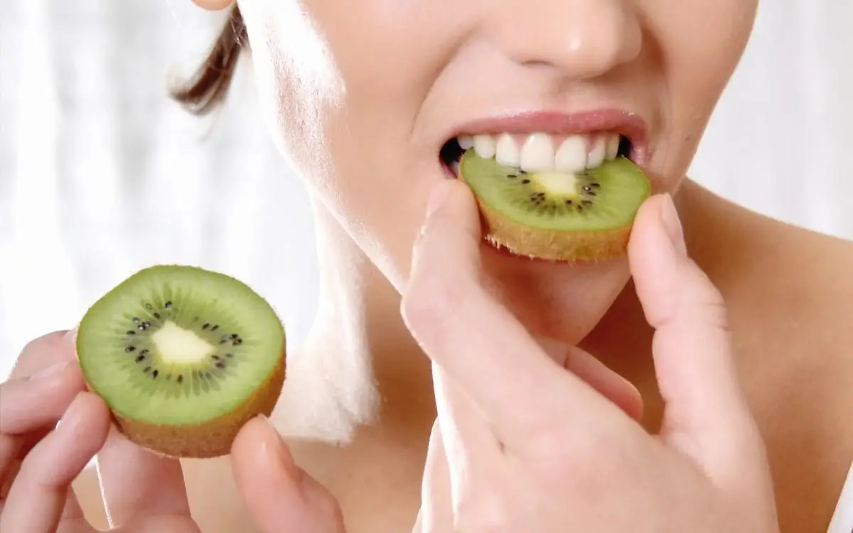 kiwi morgens oder abends essen sind kiwis entzuednungshemmend frau beisst an eine scheibe kiwi mit schale