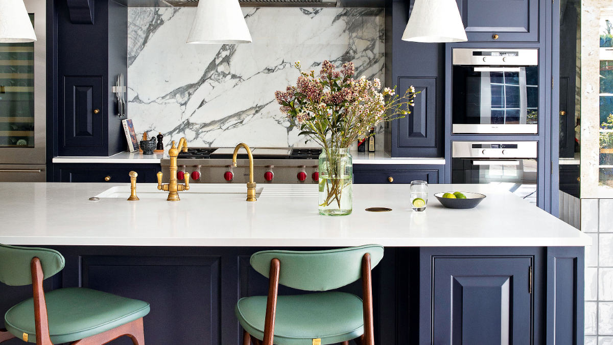 sehr gut organisierte küche mit marmor und blauen theken und vase mit blumen und goldenem waschbecken