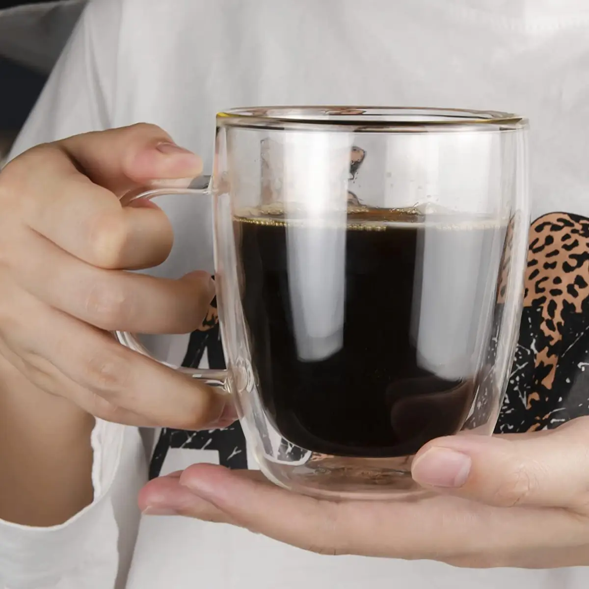 warum ist frisch gemahlener kaffee besser guten kaffee richitg zubereiten frau haelt glastasse mit doppelwand voll schwarzer kaffee