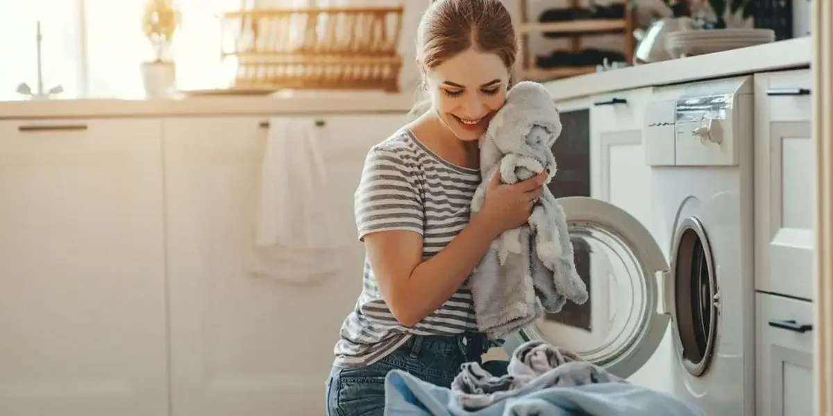 was muss ich bei einem waschtrockner beachten frau laechelnd nimmt saubere waesche aus der waschmaschine