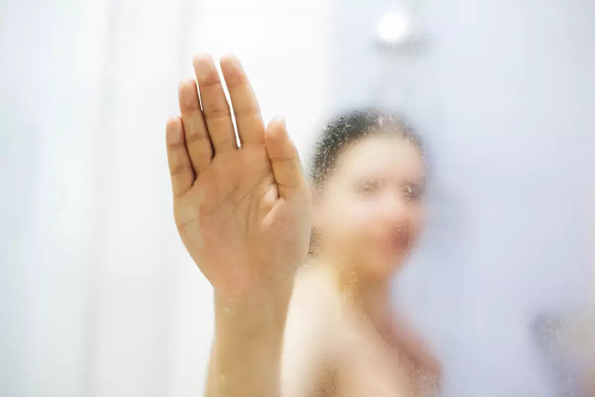 was tun bei angelaufenen spiegel frau im badezimmer nach dusche wischt beschlagenen spiegel mit hand