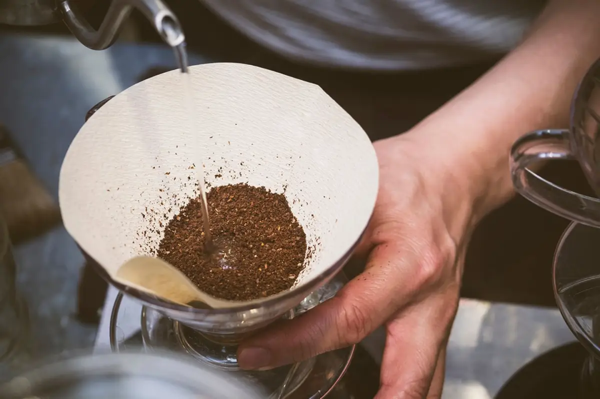 wie macht man kaffee mit einer kaffeemaschine kaffee richitg zubereiten mann giesst wasser auf kaffee in filter