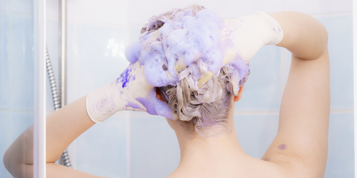 frau mit grauem haar wäscht sich mit lila shampoo für graue haare