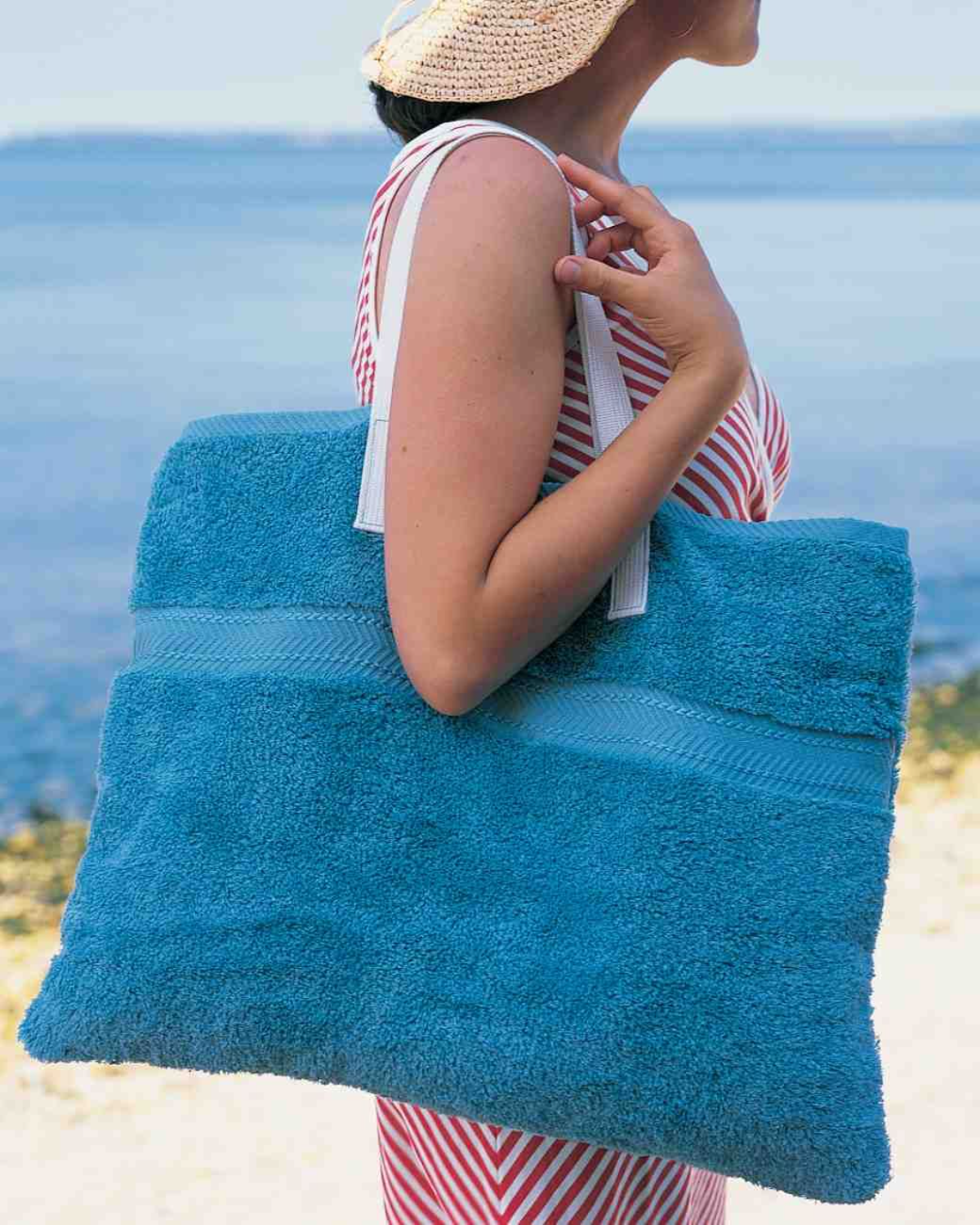 frau mit großer blauer strandtasche aus altem handtuch