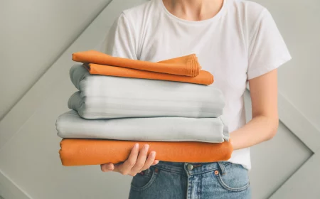 frau mit weißem t shirt und jeans hält alte bettwäsche für upcycling