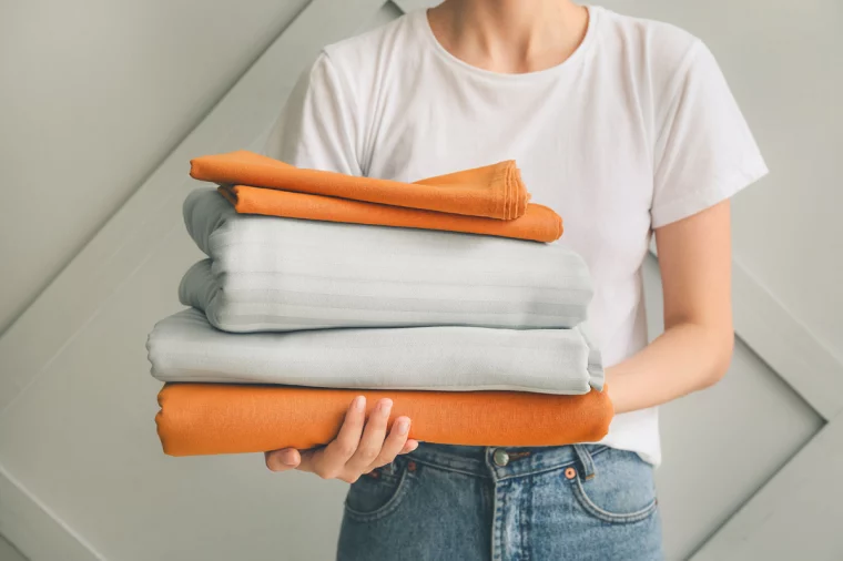 frau mit weißem t shirt und jeans hält alte bettwäsche für upcycling