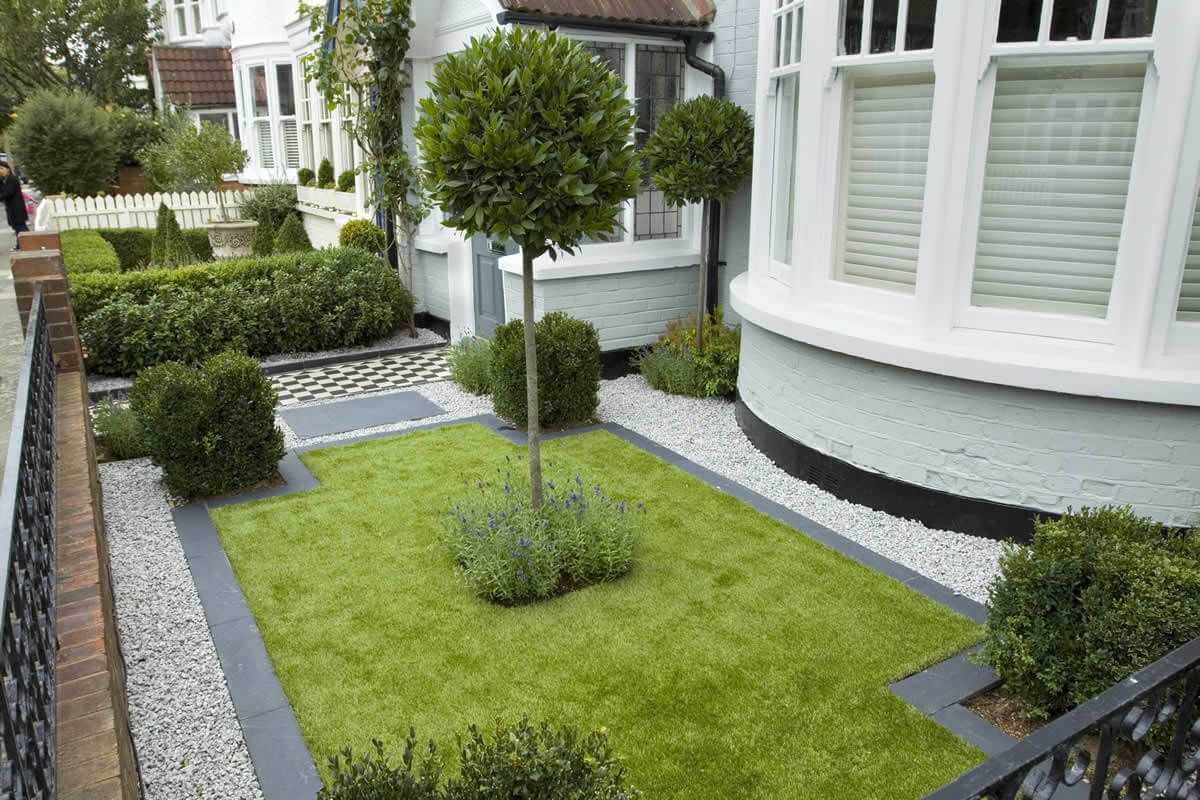 kleiner vorgarten mit rasen und sträuchern und lavendel neben den weißen fenstern