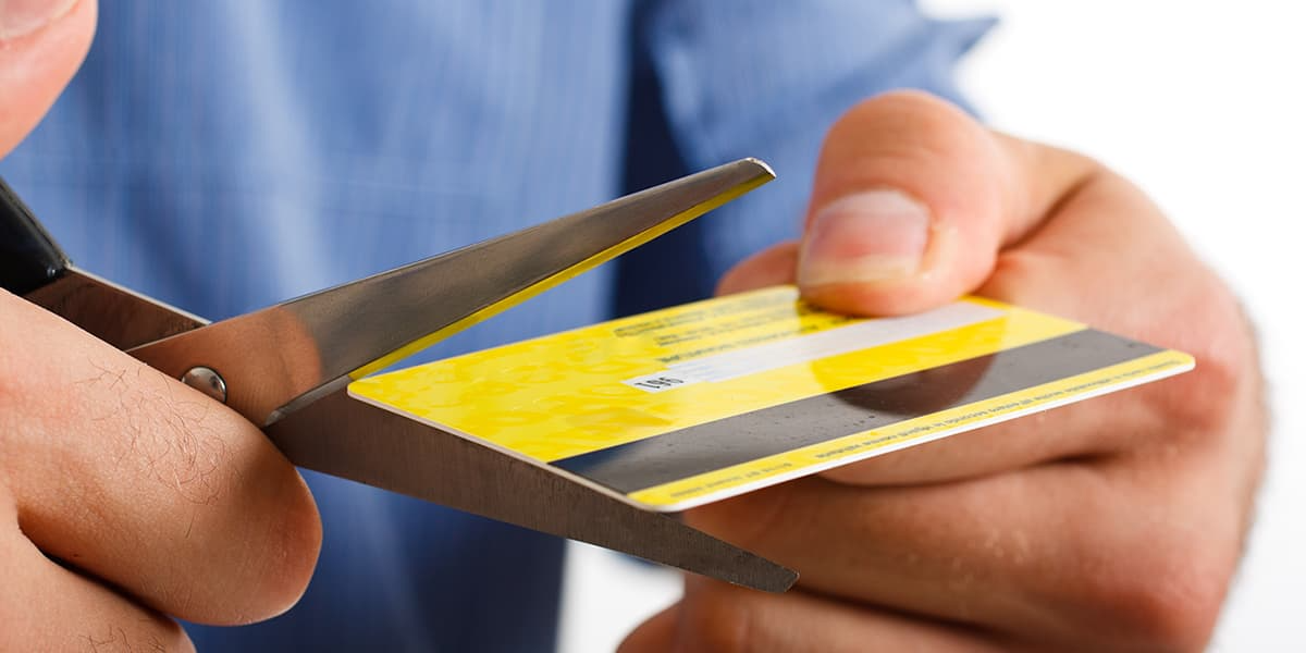 person mit blauem hemd schneidet gelbe kreditkarte aus um zecke zu entfernen