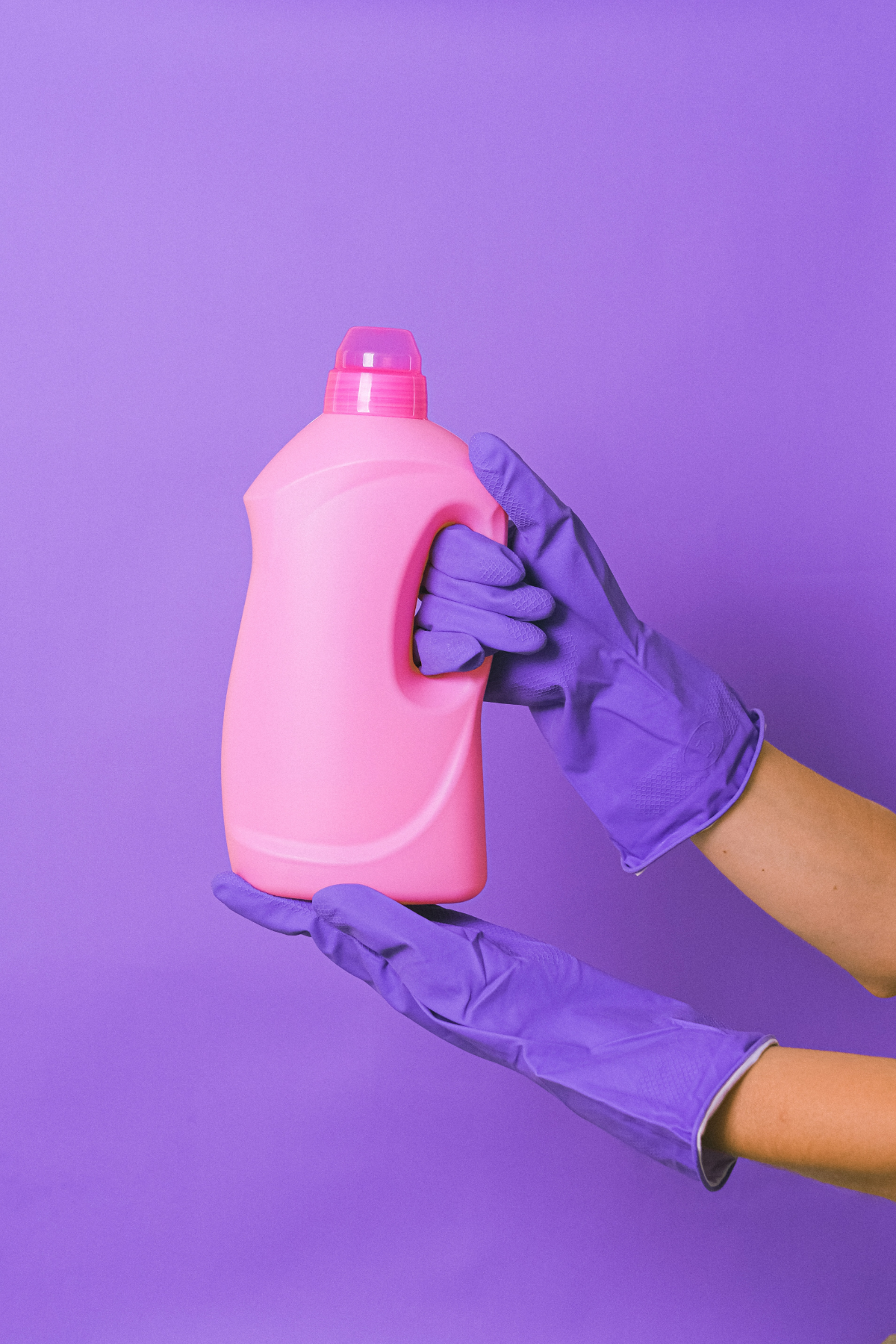 rosa waschmittel flasche aus plastik lila hintergrung haende