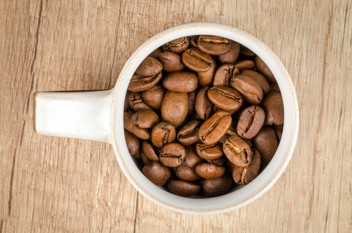 viele kaffeebohnen in weisser tassse