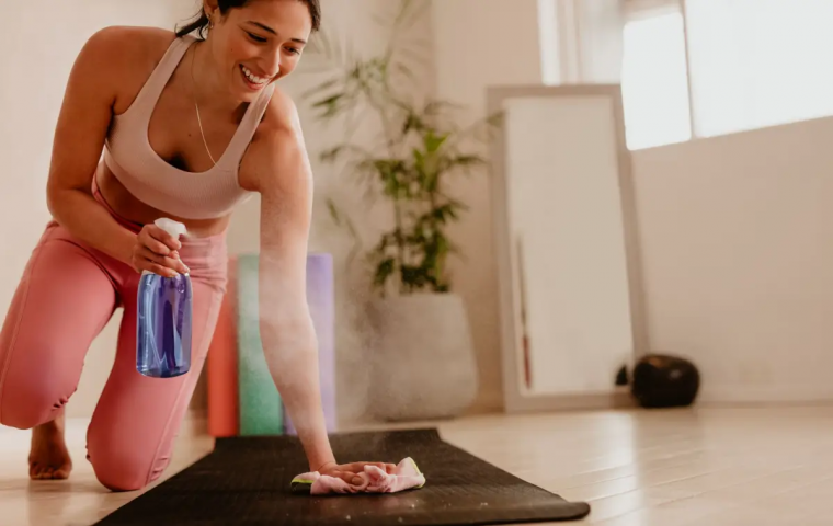 yogamatte reinigen teebaumoel frau reinigt ihre matte mit spruehflashce und weichem tuch