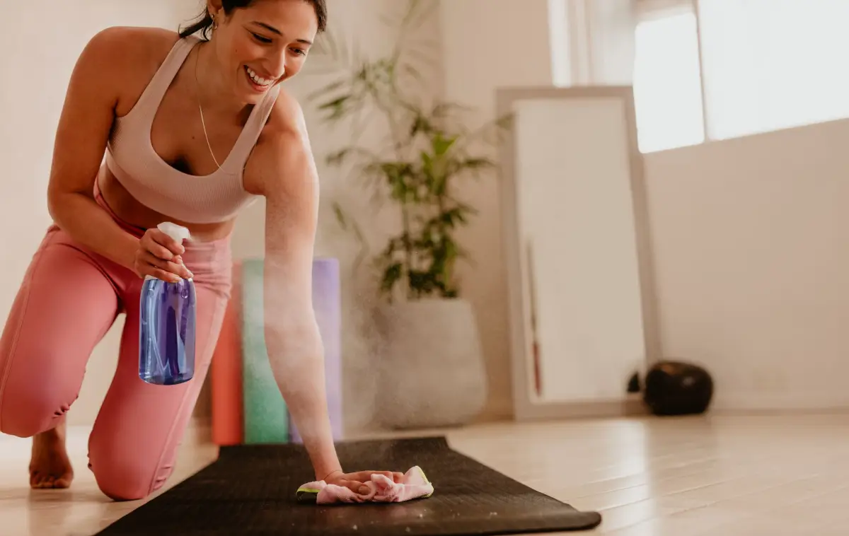 yogamatte reinigen teebaumoel frau reinigt ihre matte mit spruehflashce und weichem tuch