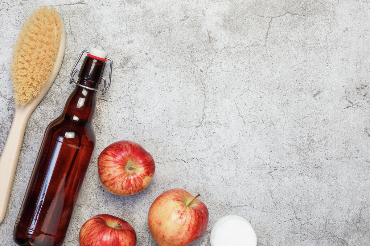 Äpfel neben einer braunen flasche neben einer hölzernen haarbürste als hausmittel gegen haarausfall