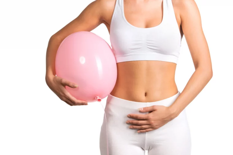 frau mit weißer kleidung hält einen rosa luftballon und ihren bauch