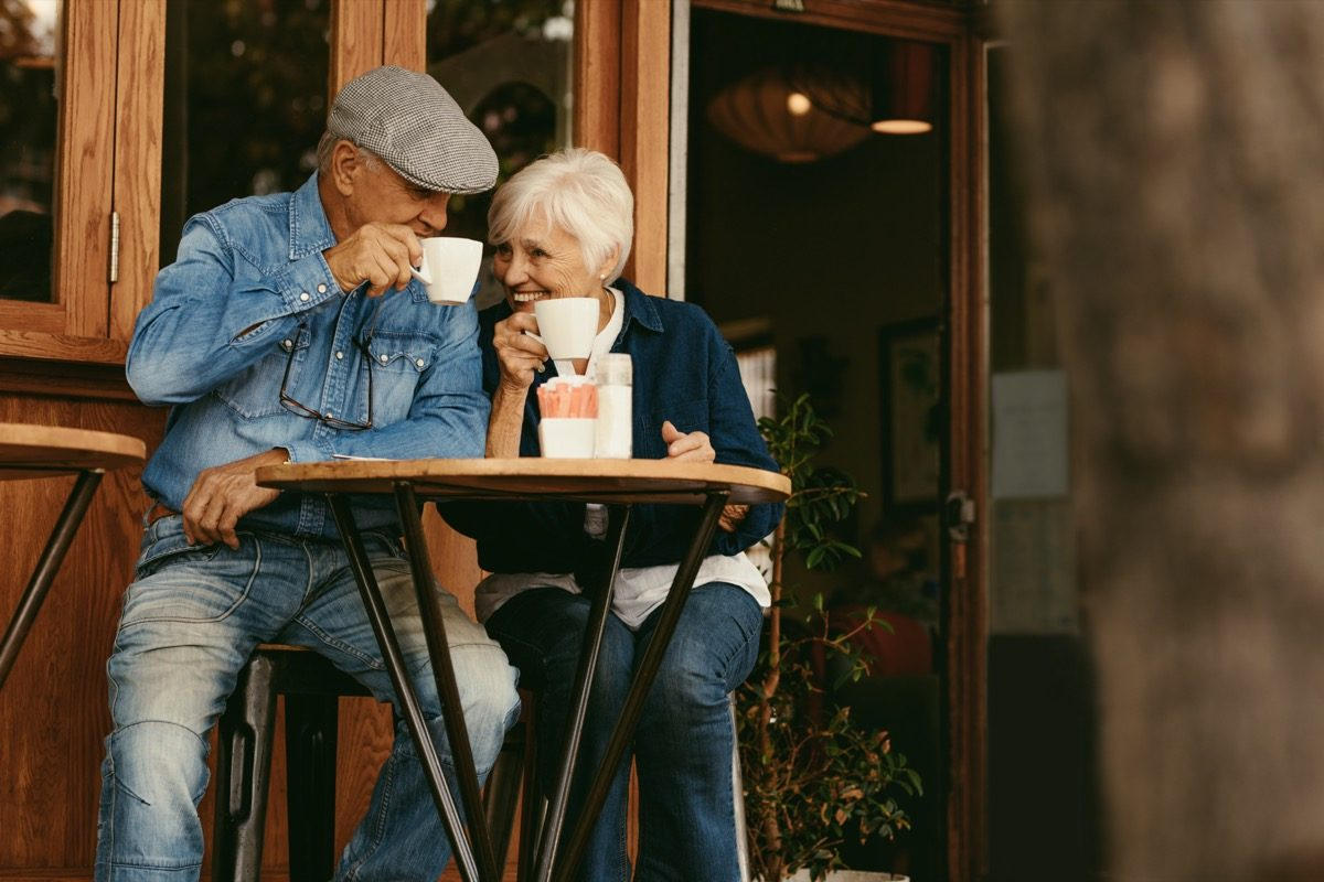 seniorenpaar trinkt draußen kaffee und lächelt