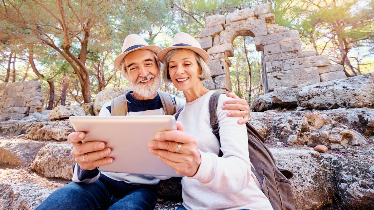 älteres paar macht ein selfie mit tablet vor einer touristenattraktion