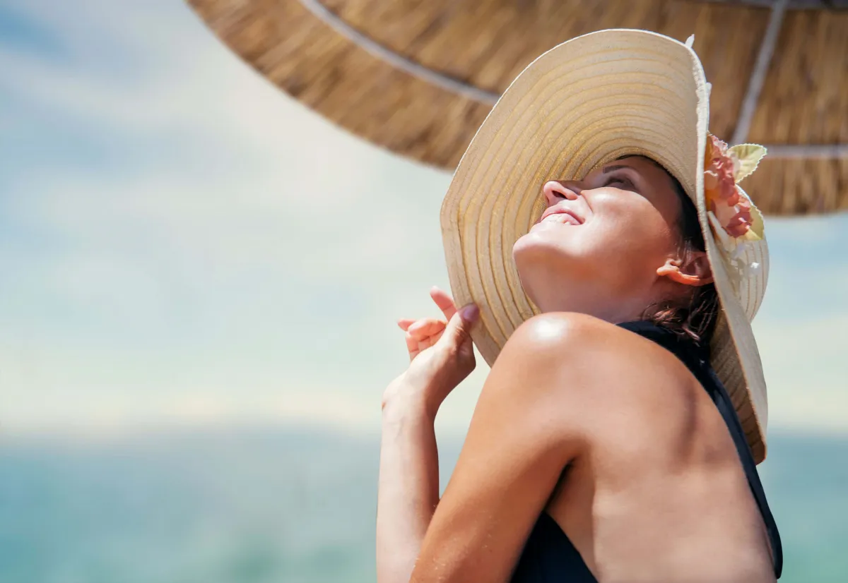 hautpflege im summer schädliche auswirkungen uw strahlen frau am strand sommerhut
