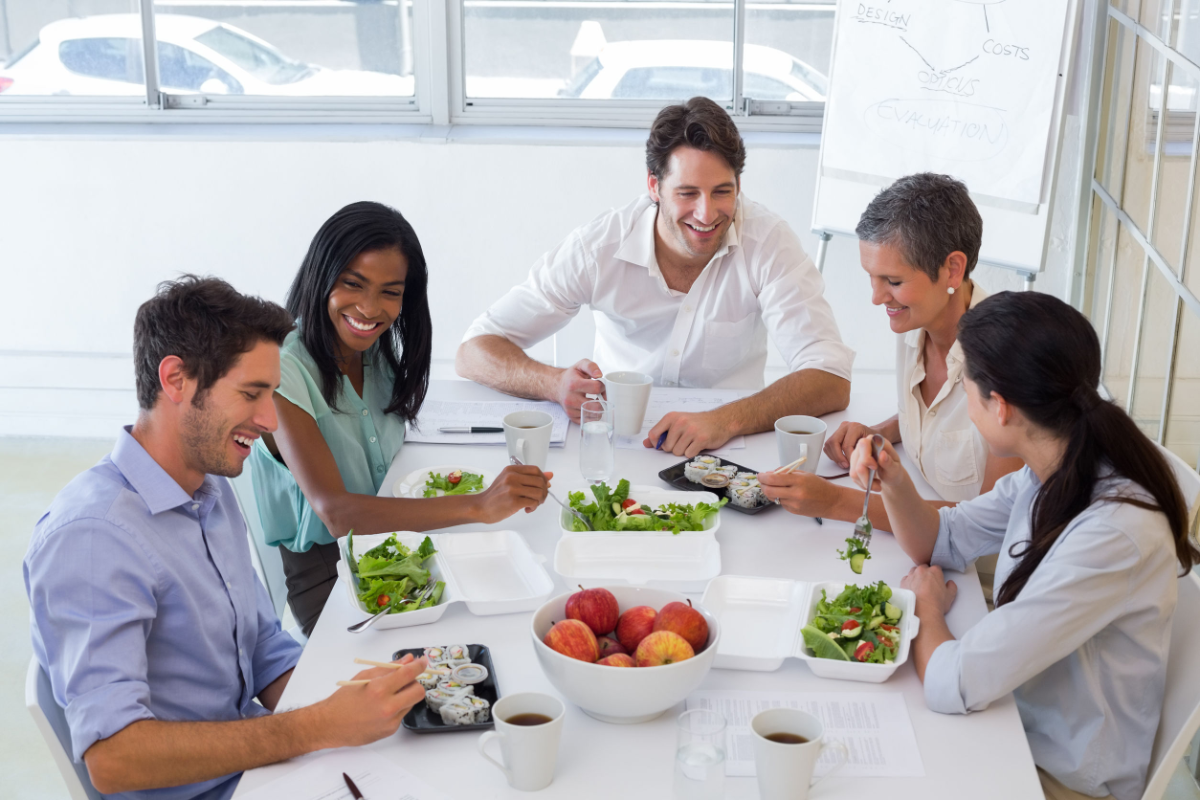 kollegen essen gemeinsam salat und sushi im büro am weißen tisch