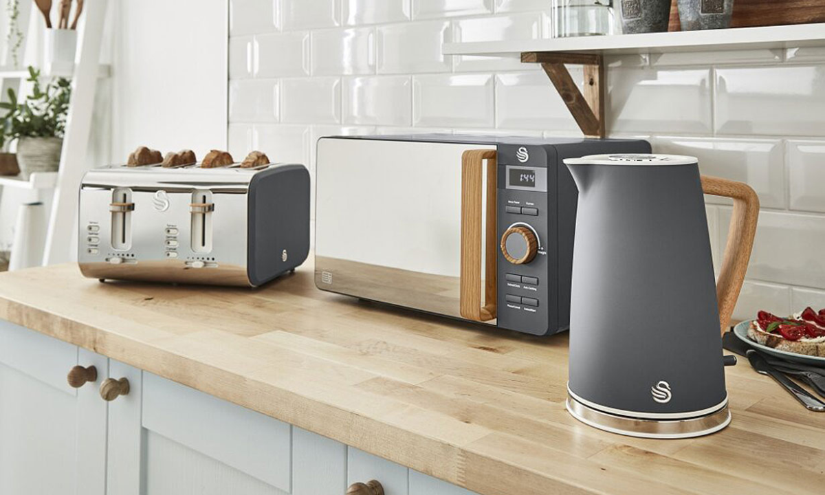 grauer wasserkocher mikrowelle und toaster in passenden farben vor weißen fliesen
