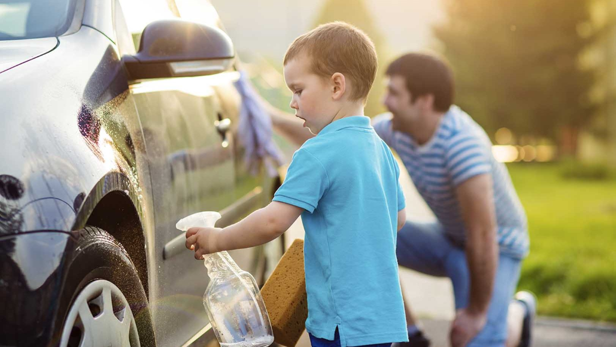 kleiner kind mit blauem t shirt wäscht auto mit seinem vater