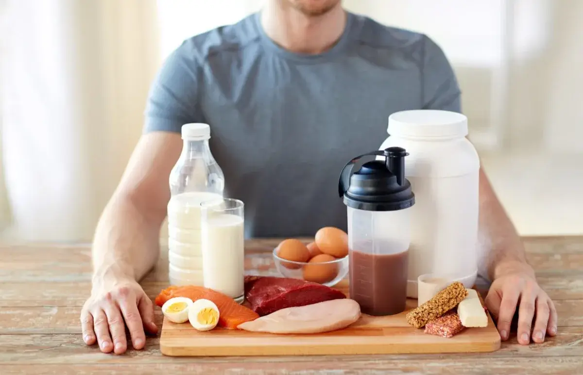 was passiert wenn man zu viel protein isst schaedlich mann sitzt am tisch lebensmittel reich an eiweiss