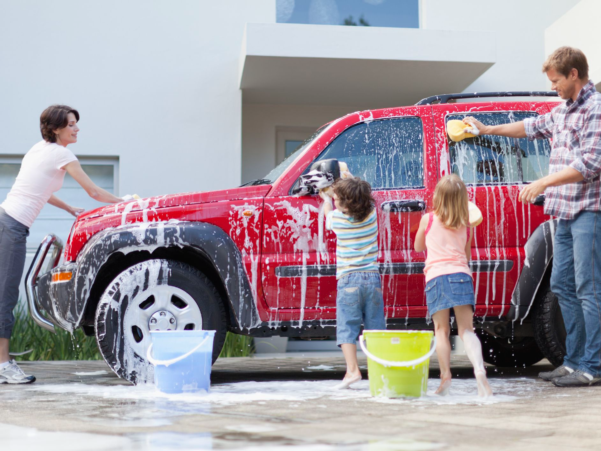 zwei kinder mit mutter und vater waschen rotes auto