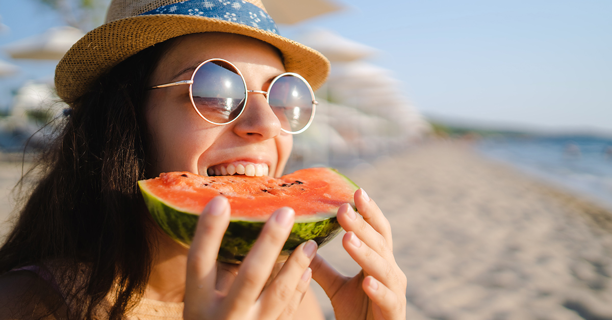 frau mit sommerhut und sonnenbrille isst im sommer wassermelone