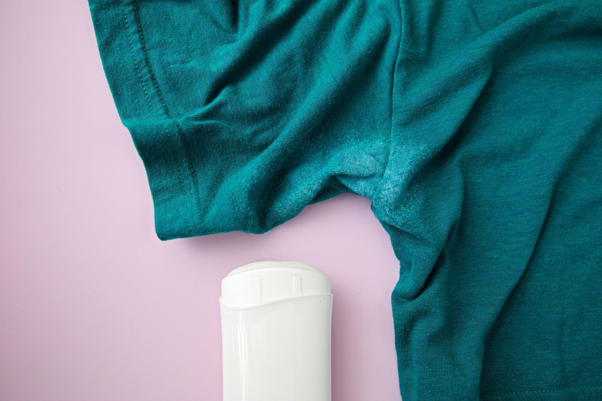 grünes t shirt mit weißem fleck neben dem deodorant