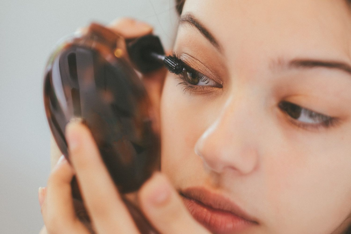 mädchen trägt mascara auf ihre natürlich langen wimpern auf