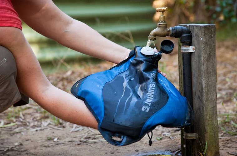 mann gießt wasser in blauen sack für camping