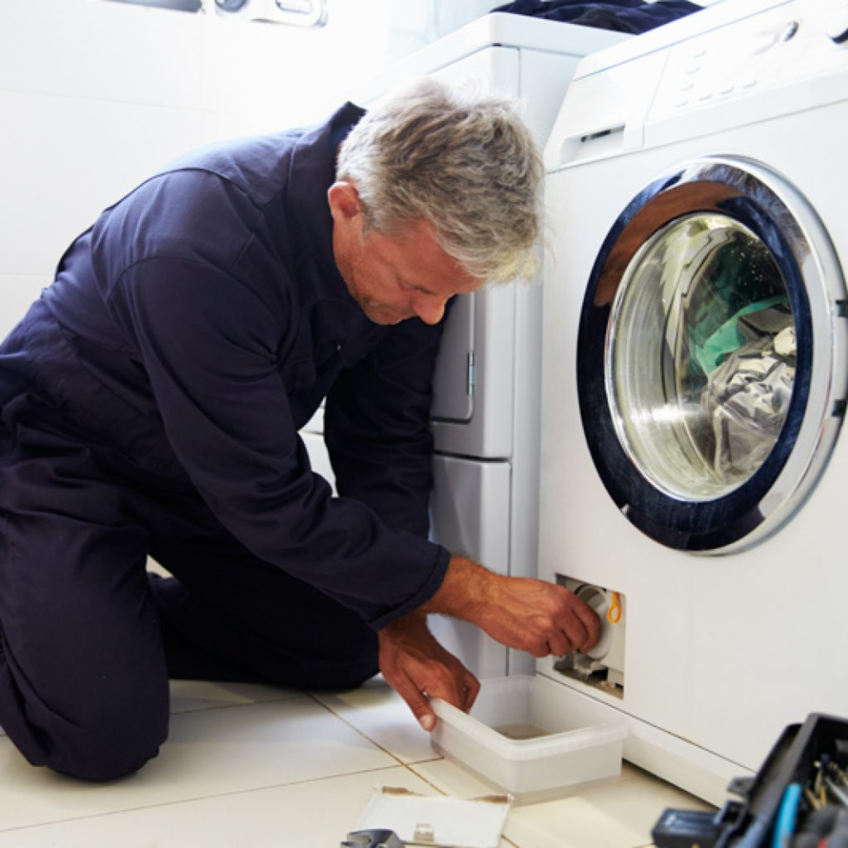 mann reinigt den filter der waschmaschine