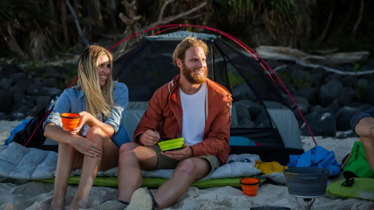 was kann man beim camping gut essen campen im sommer tipps mann und frau sitzen vor einem zelt