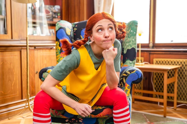 frau als pippi langstrumpf verkleidet auf buntem stuhl sitzend