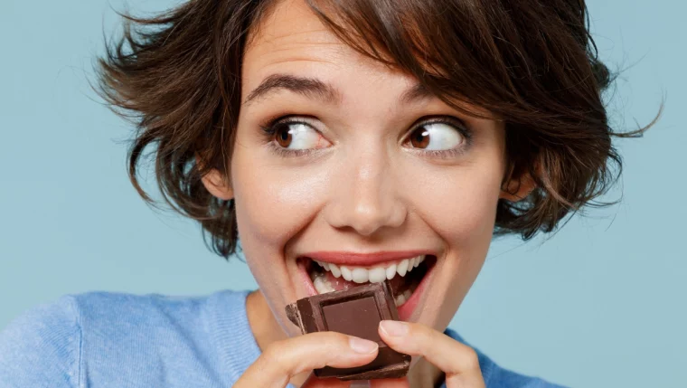 frau mit kurzen haaren isst ein stück schokolade, um stress zu reduzieren