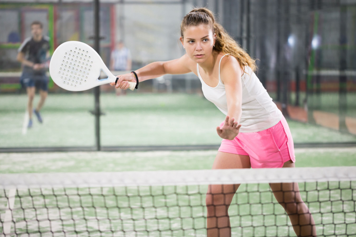 frau mit rosa und weißer kleidung spielt padel