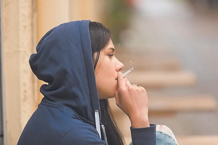 nikotin entzugserscheinungen junge frau in sweatshirt raucht