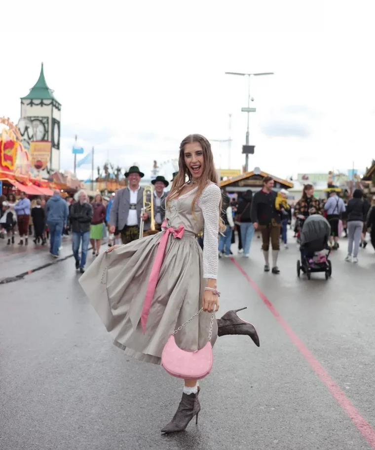 schoene dirndl waehlen dirndl trends 2023 frau in pastellgrauem dirndl rosa tasche und guertel