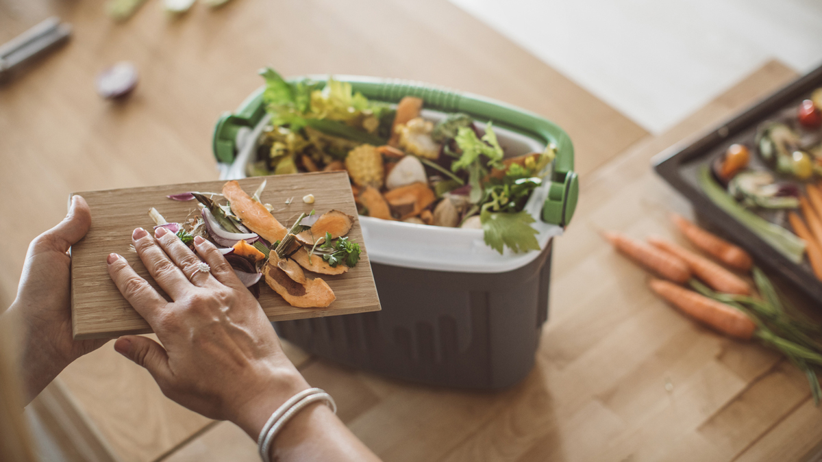 frau kompostiert essensreste in der küche, um den müll im alltag zu reduzieren