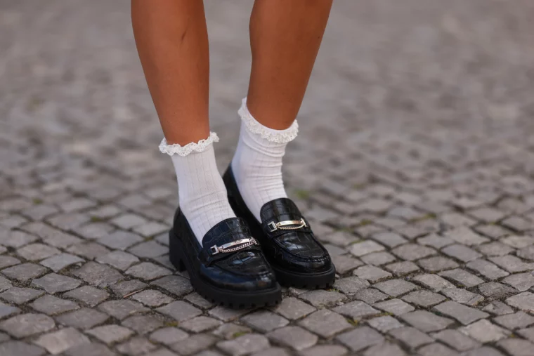 frau mit schwarzem loafer und weißen socken