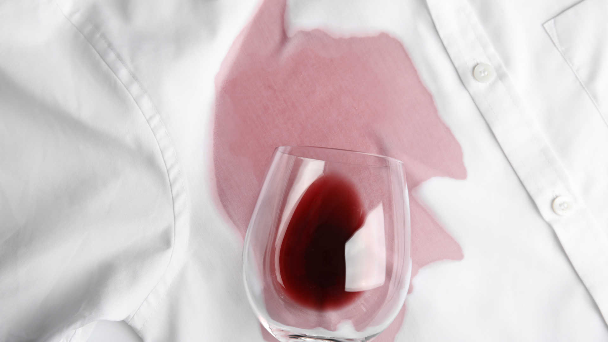 glas mit rotwein auf weißem hemd verschüttet