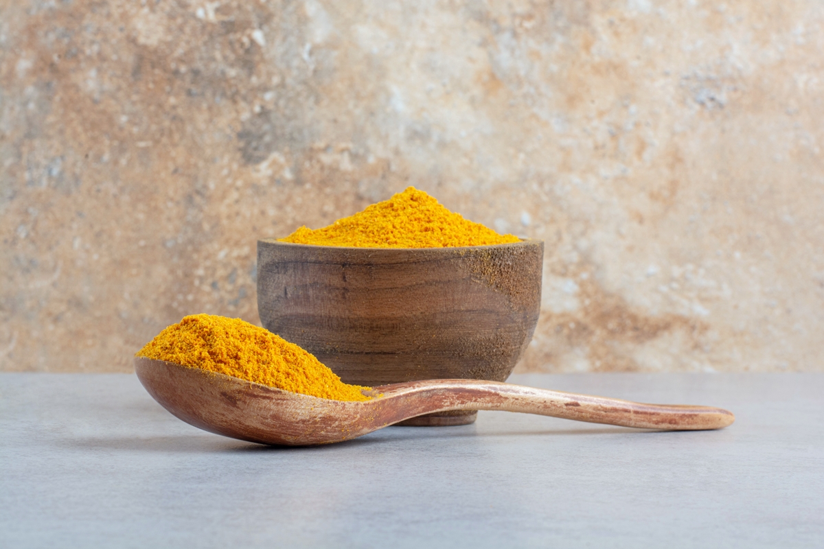 blended curcumin powder in a wooden spoon