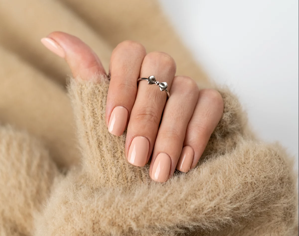 graceful thin fingers girl with trendy pastel nude manicure fluffy soft sweater cute silver ring bow