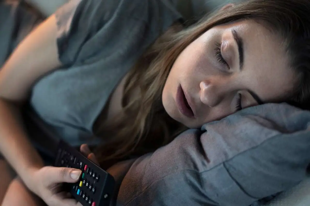 sich gesund schlafen optimale schlafdaueer frau schlaeft haelt fernsteuerung fuer fernseher